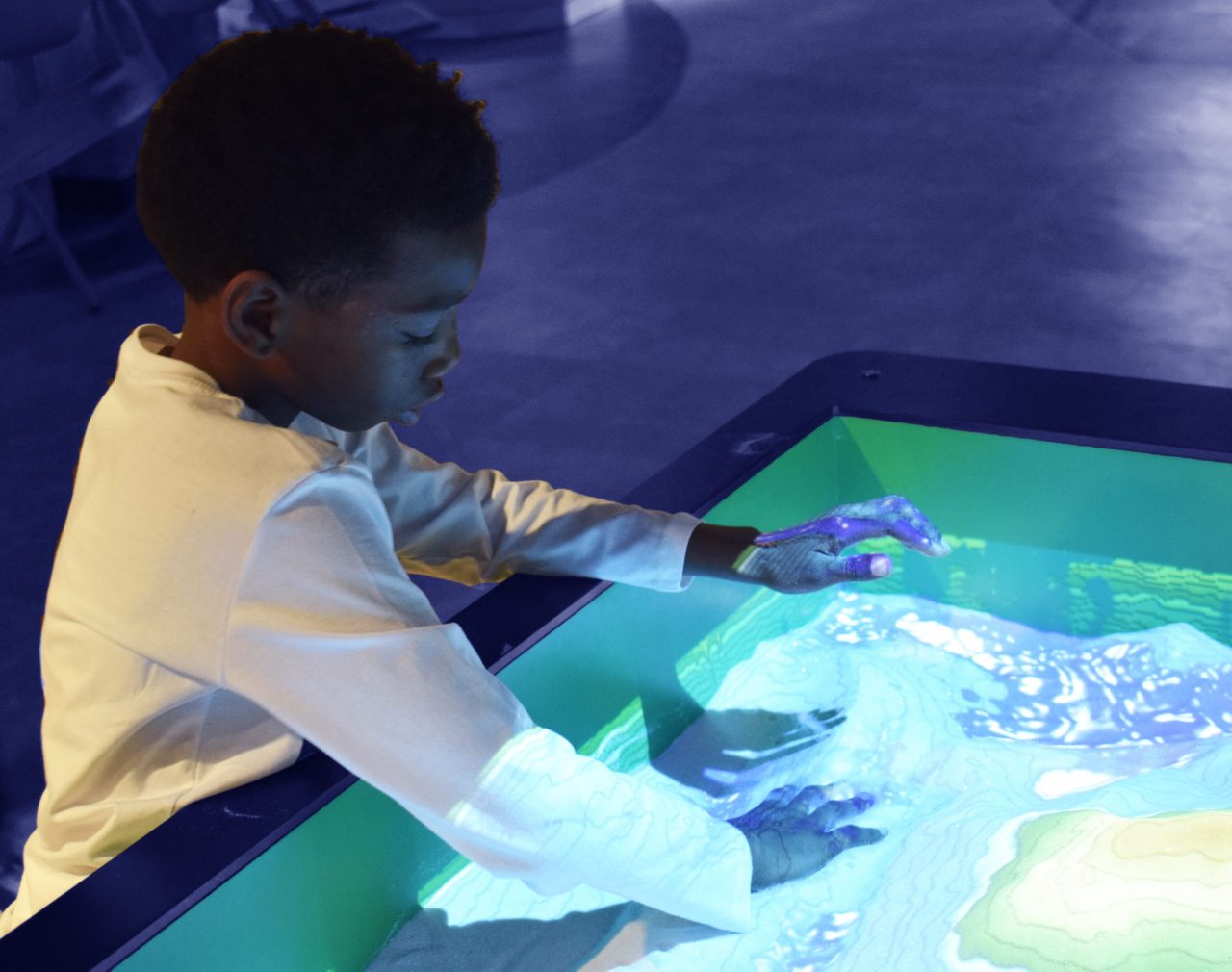 a child playing with his hands in the sand-filled terrabox